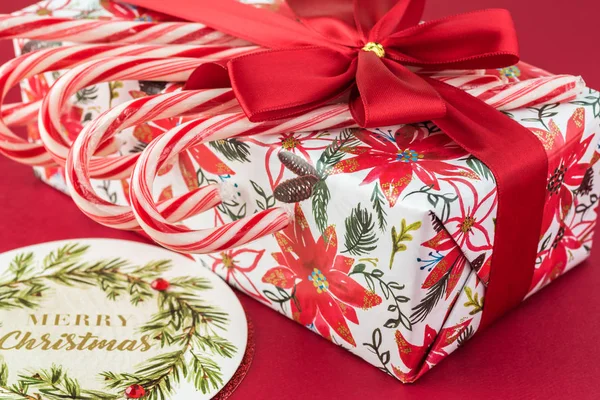 Şeker kutusu Noel kağıt sarma, kırmızı arka plan - Noel için hediye üzerinde kırmızı yay ve şeker kamışı ile dekore edilmiştir. Tebrik kartı kavramı.