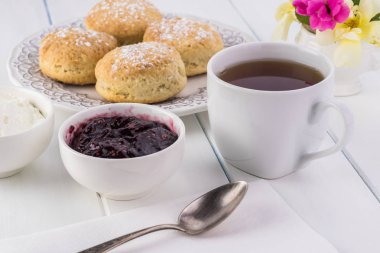 Ahududu reçeli, kaymak ve çay lezzetli İngilizce çörekler, yakın çekim.