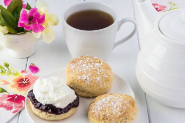 Ahududu reçeli, kaymak ve çay lezzetli İngilizce çörekler, yakın çekim.