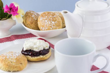 Ahududu reçeli, kaymak ve çay bardağı ile lezzetli İngilizce çörekler, yakın çekim.