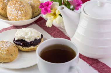 Ahududu reçeli, kaymak ve çay lezzetli İngilizce çörekler, yakın çekim.