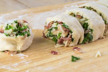 Peynirli pastırma tatil içine karışık dolguları ile hamur rulo kesme kesme tahtası üzerinde rulo.