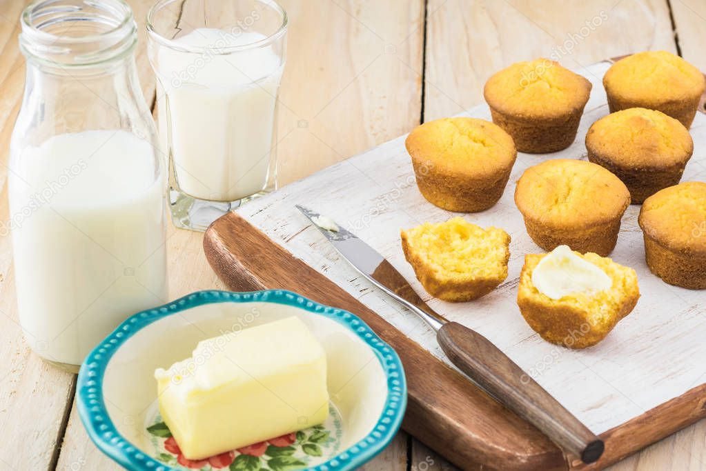 Mini cornbread muffins on a cutting board and glass of milk.