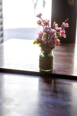 Small Vase of Pink Flowers on a Polished Wooden Table with Backlight