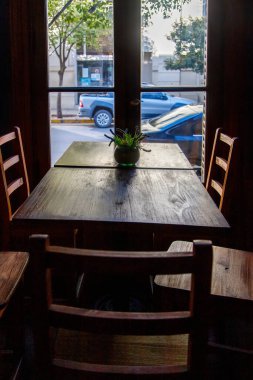 Dışarıdaki karanlık bir kafenin penceresinden masa, sandalye ve sokağa bak.