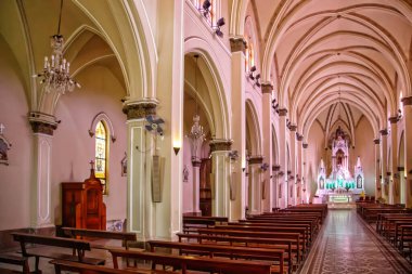 Yüksek tavanlı, sıralı sıralı ve uzakta sunağı olan bir kilisenin içi.