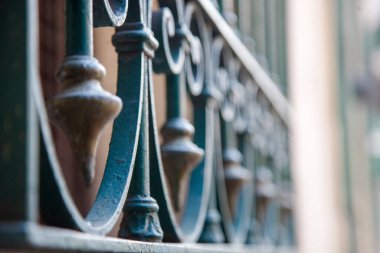 Yakından ve sığ bir alan derinliğinde süslü demirden çitler ya da yeşil boyalı bir kapı..