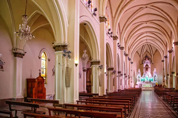 Yüksek tavanlı, sıralı sıralı ve uzakta sunağı olan bir kilisenin içi.