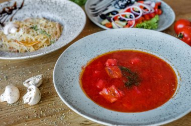 Ukrayna kırmızı borş; bir tabakta kırmızı çorba; gıda fotoğrafçılığı; ev Ukrayna mutfağı; kafe menüsü için; iş öğle yemeği; yağlı gıdalar; yemek tabakları ahşap masa üzerinde;