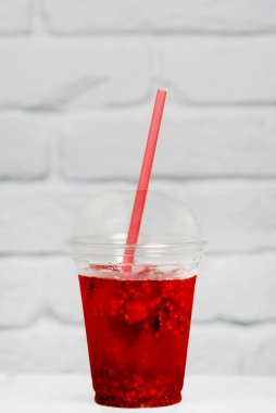 Yaz ferahlatıcı limonatayı servis bardağında beyaz tuğladan bir duvara yapıştırıyor.