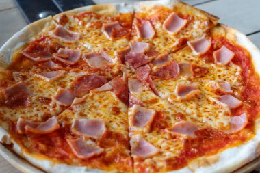 Yakın çekim pizza jambon peynir domates kaynakları ahşap tepsi ile