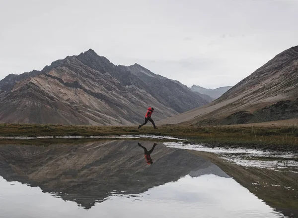 水の上の湖と山の風景 そして反射を飛び越えて男 — ストック写真