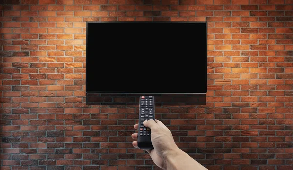 Televisie Bakstenen Muur Met Hand Met Afstandsbediening — Stockfoto