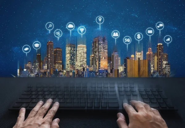 Computer networking and internet connection. Hand typing computer keyboard and buildings with social networking and application icons