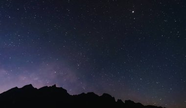 Gece gökyüzünde yıldızlar ve Samanyolu, siluet dağ ile dolu