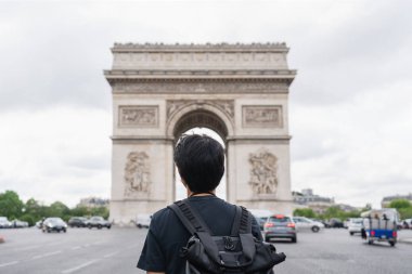 Sırt çantası ile bir adam Arc de Triomphe, ünlü dönüm noktası ve Paris, Fransa seyahat hedef bakarak. Yaz aylarında Avrupa'da seyahat