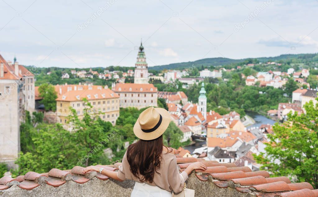 Young traveler woman in hat looking at city view of Cesky Krumlov, Czech Republic in summer. Traveling europe in summer