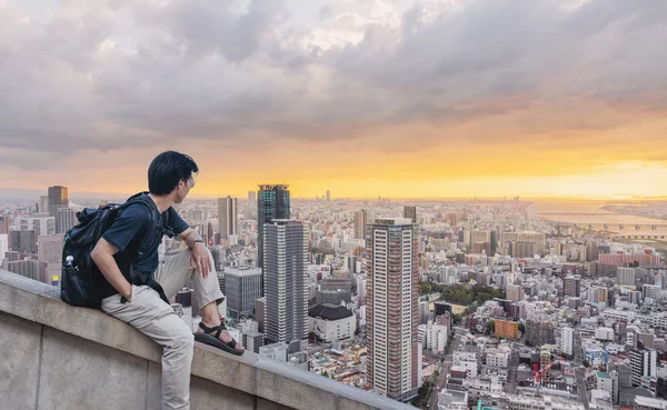 sırt çantası ile yaz aylarında gün batımında şehir görünümüne bakan bir adam