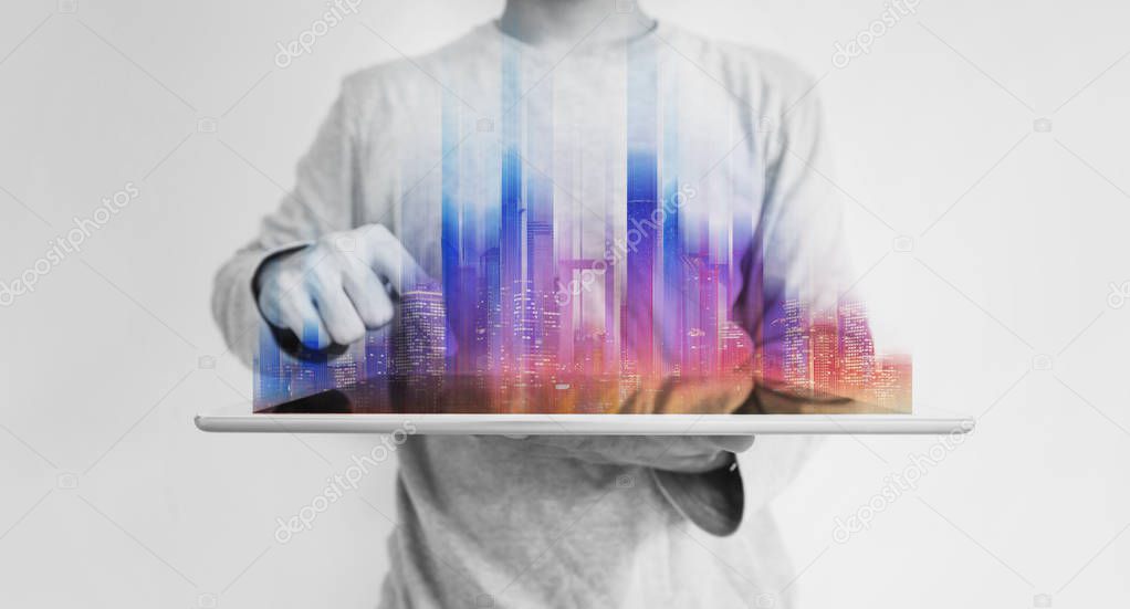 Futuristic man holding digital tablet with colorful modern building hologram, on white background