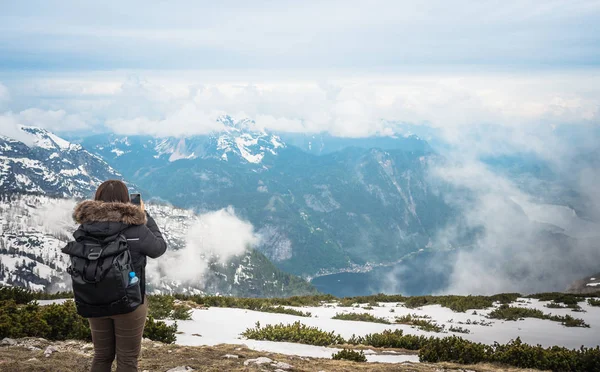 オーストリア ハルシュタットの携帯電話で夏のアルプス山脈の写真を撮るバックパックを持つ旅行者 — ストック写真