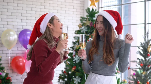 Asian women dancing and drinking champagne in Christmas party. Christmas holiday celebration