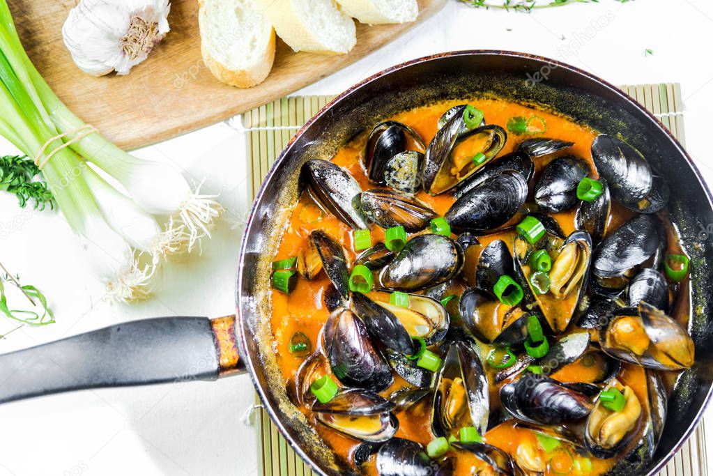  Delicious seafood mussels with red sauce and green onions in a pan