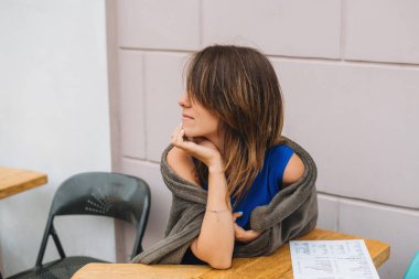 Bir kız yazlık terasta oturmuş siparişini bekliyor.