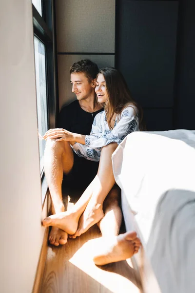 Un hombre y una chica están sentados en el suelo y mirando por la ventana — Foto de Stock