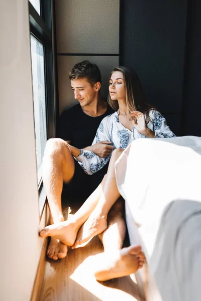 Un hombre y una chica están sentados en el suelo y mirando por la ventana — Foto de Stock