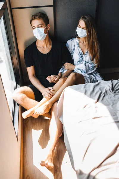Мужчина и девушка сидят на полу в масках на лицах Лицензионные Стоковые Изображения