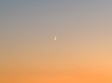 Akşam Gökyüzündeki Hilal Ay: Işıl ışıl parlayan ince bir hilal ışığının sakin bir görüntüsü alacakaranlıkta yumuşak, eğimli bir gökyüzüne vurularak, barışçıl geçişi gece gündüz yakalıyor..