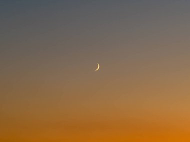 Akşam Gökyüzündeki Hilal Ay: Işıl ışıl parlayan ince bir hilal ışığının sakin bir görüntüsü alacakaranlıkta yumuşak, eğimli bir gökyüzüne vurularak, barışçıl geçişi gece gündüz yakalıyor..