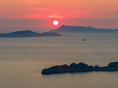 Yunanistan 'ın Korfu kentinden İyon Denizi üzerinde sakin bir günbatımı. Kızıl güneş uzak Diapontia Adaları 'nın arkasına batar ve güzel ve sakin bir yaz akşamı deniz manzarası yaratır..