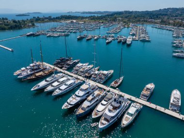 Aerial view of impressive superyachts and luxury motorboats moored at a pier in Gouvia Marina, Corfu, Greece. A symbol of wealth, luxury lifestyle, and exclusive summer travel