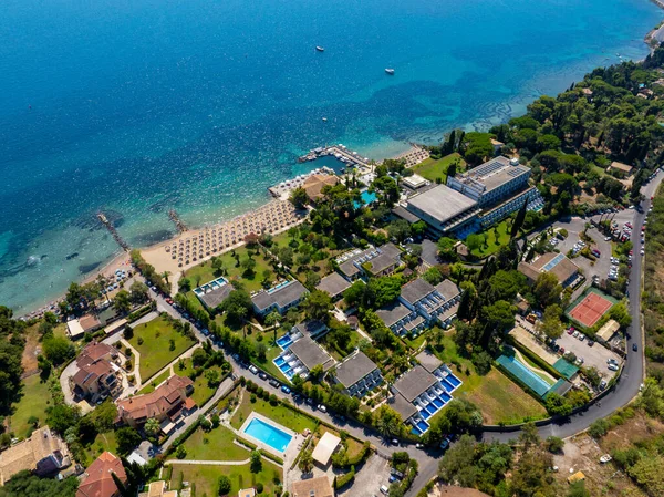 Yunanistan 'ın Korfu kentinde lüks bir sahil beldesinin insansız hava aracı görüntüsü. Turkuaz suyu, özel havuzları ve mükemmel bir yaz tatili ve seyahat yeri için kumlu plajı olan güzel bir sahil şeridi.