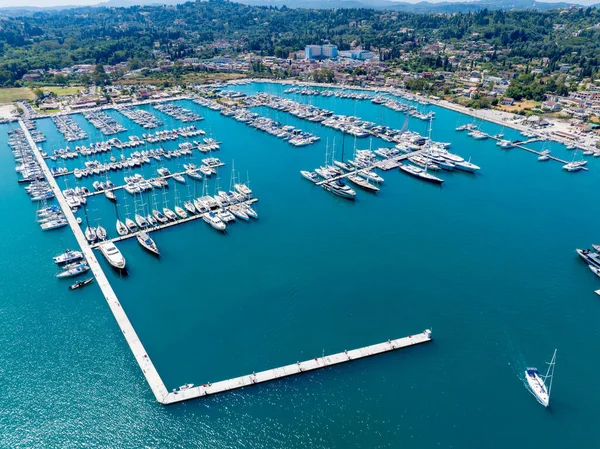 Sweeping aerial drone view of Gouvia Marina in Corfu, Greece. A major Ionian Sea port filled with luxury yachts and sailboats, representing a prime summer travel destination in September
