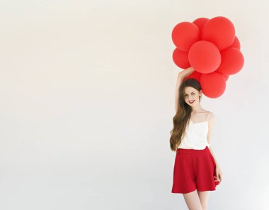 beyaz zemin üzerine kırmızı balonlarla çekici genç kadın