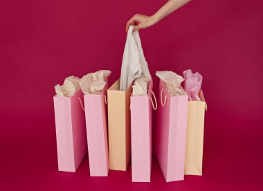 birkaç kağıt poşetler pembe arka plan, kadın el üzerinde görüntü