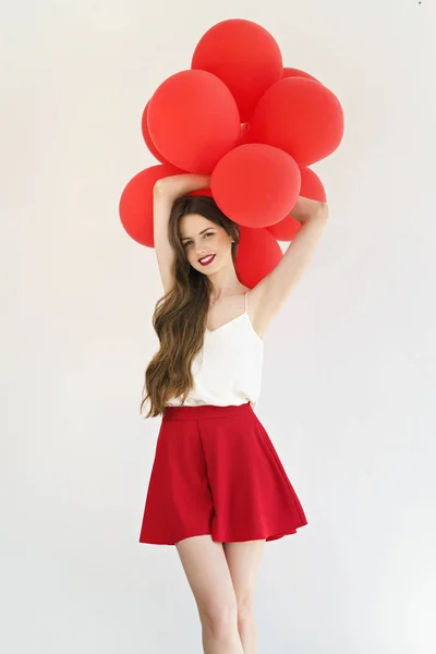 attractive young woman with red balloons on white background