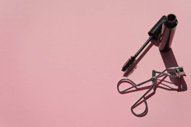 Black mascara with curler  on pink  background  clipart