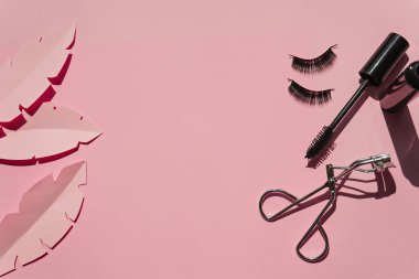 Black false lashes strips,mascara, curler on pink background  clipart