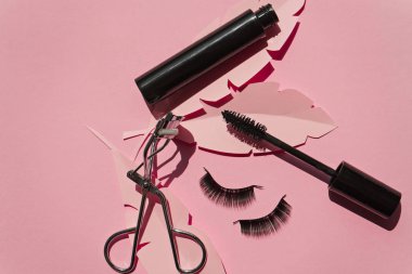 Black false lashes strips,mascara, curler on pink background  clipart