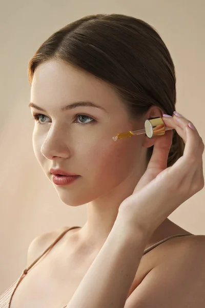 Retrato Joven Hermosa Mujer Aplicando Aceite Cosmético Cara Posando Sobre —  Fotos de Stock