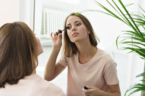 自宅の鏡の前でマスカラーを適用する若い女性 — ストック写真