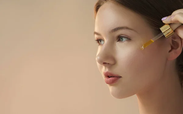 Retrato Mujer Joven Aplicando Suero Cara Sobre Fondo Beige —  Fotos de Stock