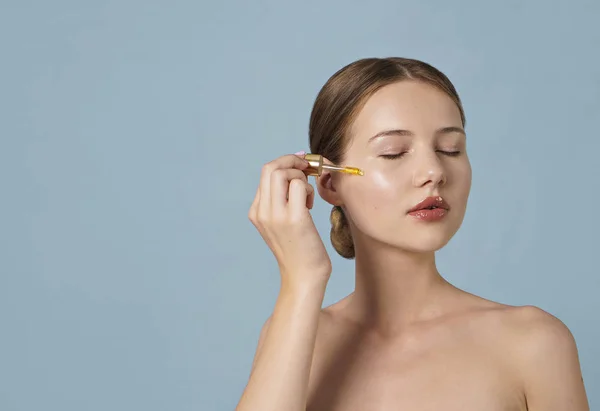 Retrato Mujer Joven Aplicando Suero Cara Sobre Fondo Azul —  Fotos de Stock