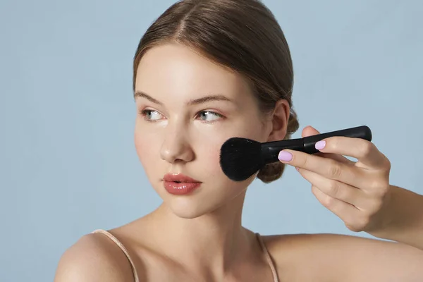 Retrato Mujer Joven Aplicando Polvo Cosmético Cara Sobre Fondo Azul —  Fotos de Stock