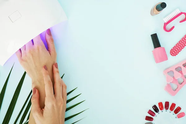 top view of female hands with glowing manicure lamp on table