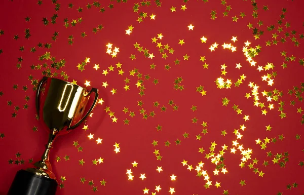 image of small gold cup with golden stars on red background