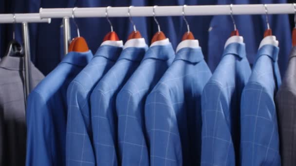 Hombres trajes y chaquetas colgando en una tienda de ropa — Vídeos de Stock